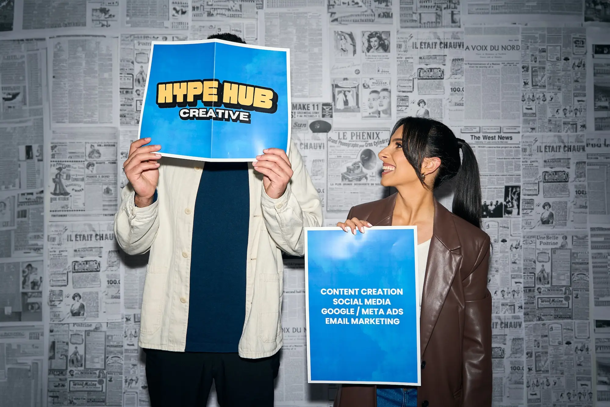 Angela and Thomas posing in front of camera holding Hype Hub Creative posters